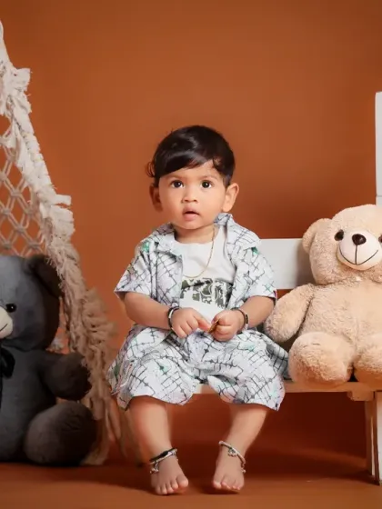 A first birthday shoot with a rustic, outdoor feel, featuring teddy bears and a teepee against a warm brown backdrop.