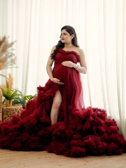 A standing portrait by the window, the natural light beautifully illuminating the flowing red gown.