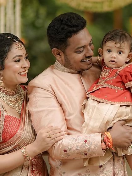 A close-up of a family sharing a happy moment. The intricate embroidery on the mother's red blouse and the father's jacket highlights the detailed craftsmanship that goes into our family twinning collections.