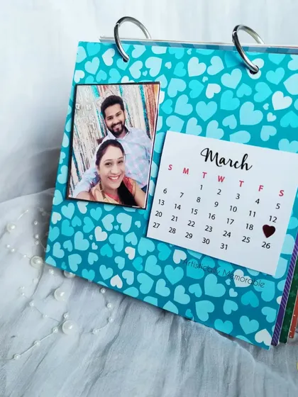 A bright blue March page from a custom desk calendar, with a heart marking a special date.