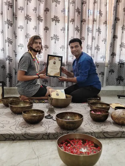 A student receives his certification, marking his entry into the world of sound therapy as a practitioner.