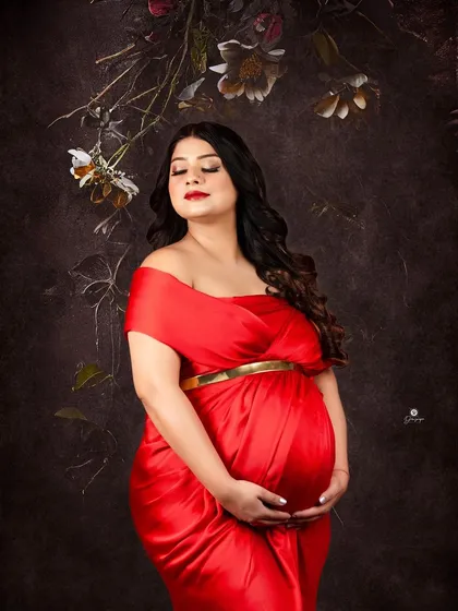 A classic and elegant portrait against a dark, painterly backdrop. The vibrant red satin gown and the client's serene expression create a timeless and sophisticated image.