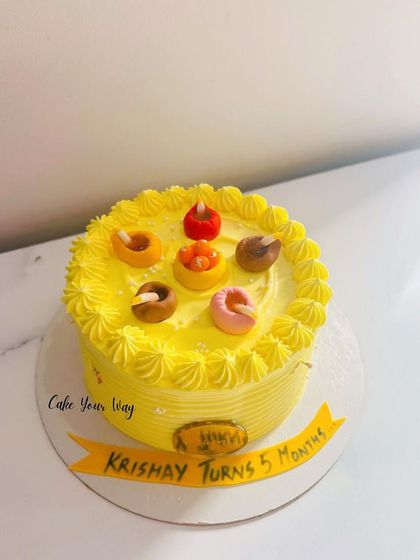 A bright yellow cake with little diyas to celebrate a 5-month milestone.
