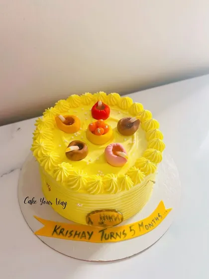 A bright yellow cake with little diyas to celebrate a 5-month milestone.