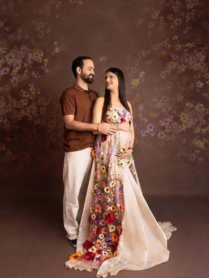 A sweet couple's portrait featuring the floral gown. The partner stands behind, creating a sense of connection and shared joy against a complementary floral background.