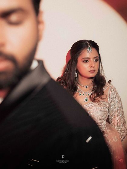 An artistic shot with the groom's blurred shoulder in the foreground, drawing focus to the bride's expression.