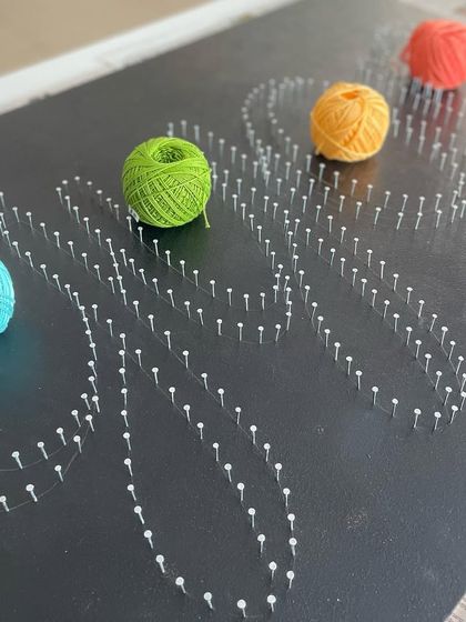 The nails are all in place, and the colorful spools of thread are ready to be used to create a vibrant, personalized nameplate.