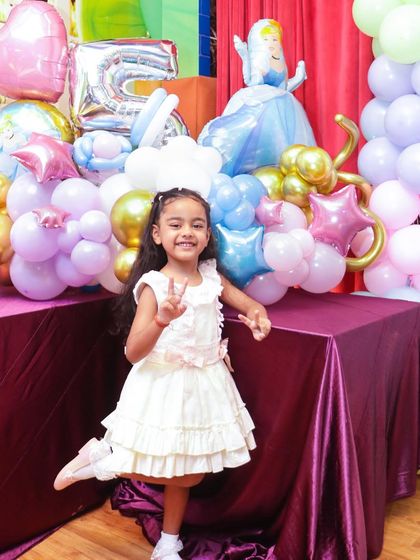 The birthday princess posing by her Cinderella-themed decorations. We ensure every detail, from the balloons to the character cutouts, matches your chosen princess theme.