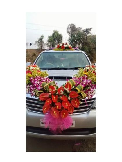 An exotic and striking car decoration for a Toyota Fortuner. This design features a bold arrangement of red anthuriums and purple orchids, creating a unique and memorable look.