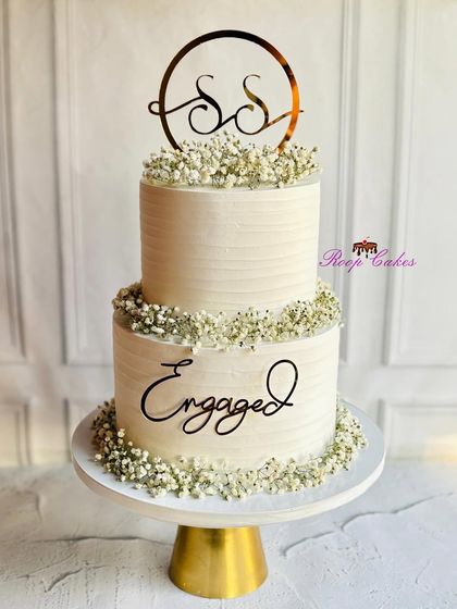 Simple elegance defines this two-tier engagement cake. The clean, textured buttercream is beautifully accented with delicate baby's breath and a custom monogram topper, proving that sometimes less is more.