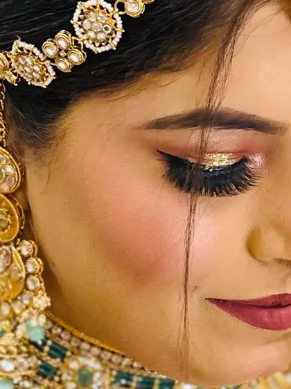An artistic close-up of bridal eye makeup. The winged eyeliner is paired with a dense set of volume lashes and a touch of gold glitter for a truly festive look.