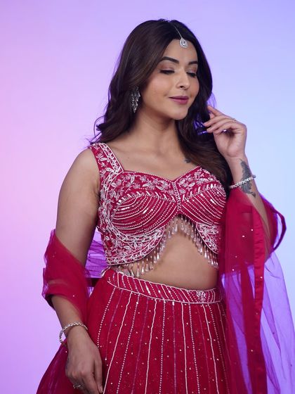 A close-up of the hot pink lehenga, focusing on the intricate beadwork and tassel details on the blouse.