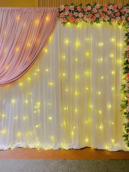 This asymmetrical design is modern and chic. The combination of a floral border, a light curtain, and a single drape creates a balanced and stylish backdrop.