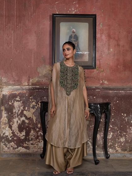 A model stands gracefully in a beige cape set, her look a perfect blend of tradition and modernity.