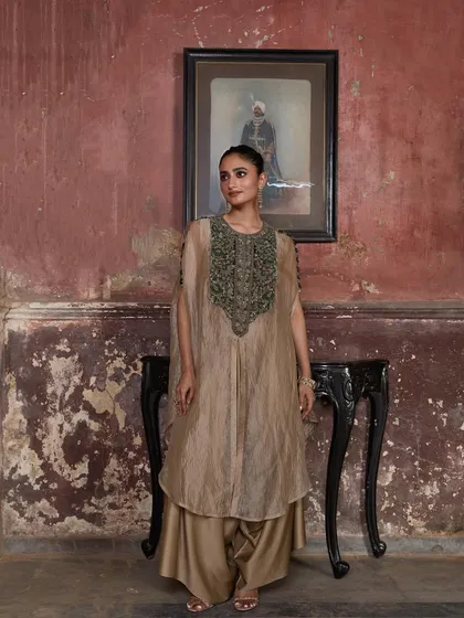 A model stands gracefully in a beige cape set, her look a perfect blend of tradition and modernity.