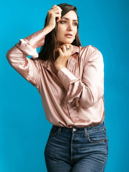 A model in a soft pink satin shirt and jeans, set against a vibrant blue background. This shot highlights my ability to create compelling color contrasts for fashion portraits.