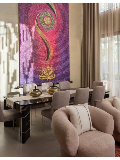 In the House of Terraces, the dining area is a double-height space anchored by a magnificent, large-scale textile artwork. The plush, curved armchairs in a soft rose fabric add a touch of glamour and comfort.