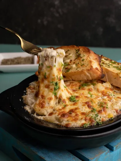 The strongest pull of all. A fork pulling up a cheesy bite of baked mac and cheese, showcasing the creamy, gooey texture of the dish.