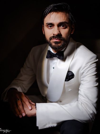 A moody, classic portrait of the groom in his white tuxedo jacket.