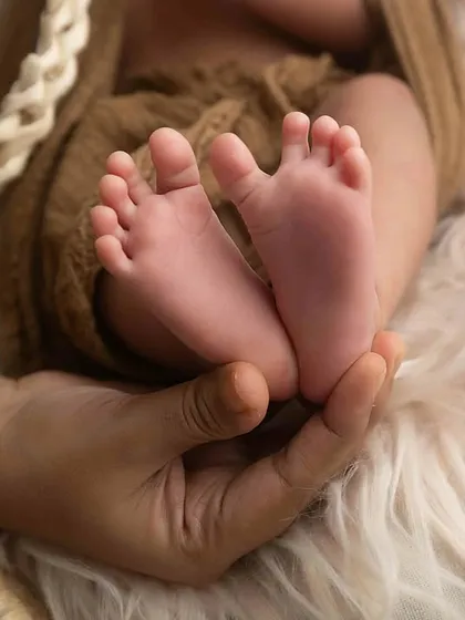 A close-up of perfectly tiny newborn toes, held gently in a mother's hand. These detail shots are just as important as the full portraits.
