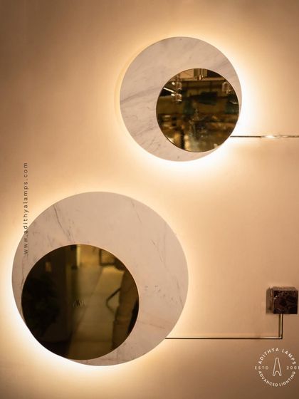 A modern wall sconce featuring a disc of white marble with a gold-mirrored circular cutout. The backlight provides a soft, ambient halo, making it a sophisticated and elegant choice for hallways or flanking a master bed.