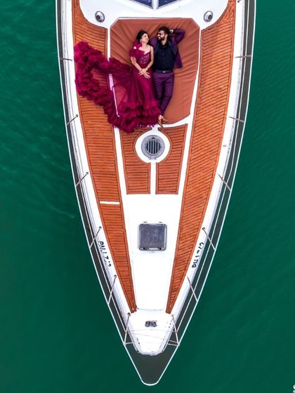 An incredible aerial drone shot of the couple lying on the deck of a yacht, with the magenta gown spread around them.