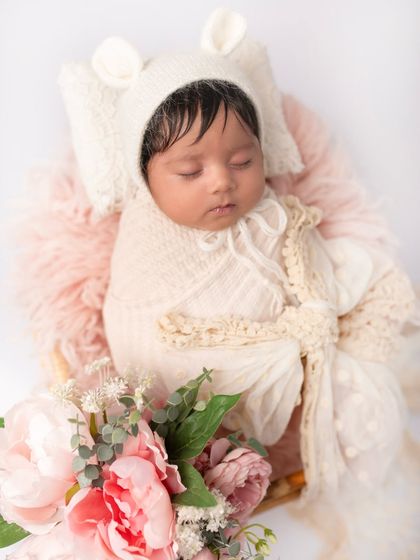 Wrapped in soft lace and wearing a tiny bear bonnet, this newborn is sleeping soundly. The textures and layers add so much depth to the portrait.