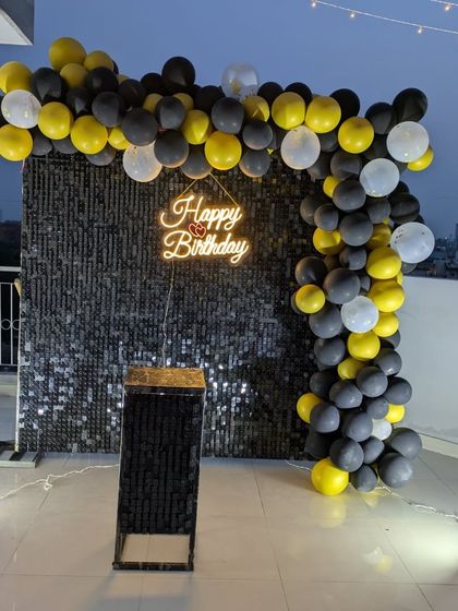 This wide shot shows how the sequin wall and balloon arch create a defined party corner on an open rooftop.
