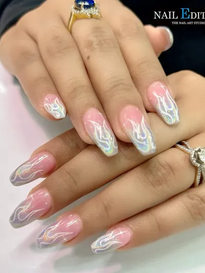 A subtle yet stunning flame design. This set uses a pearlescent, holographic chrome to draw delicate flames over a soft pink and gray gradient base on long square nails.