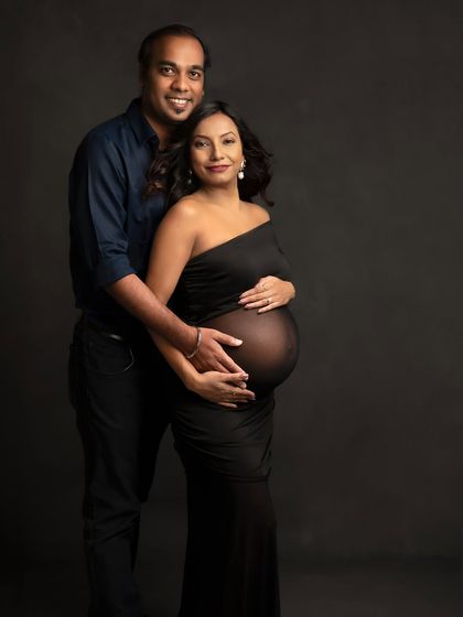 A timeless and classic portrait. Both partners looking at the camera, sharing this moment with the world, their hands together on the bump.