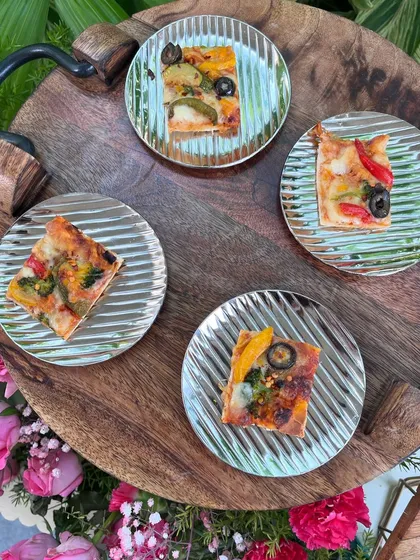 Mini pizzas on silver-striped plates, offering a familiar and delicious bite for guests at a relaxed pool party.