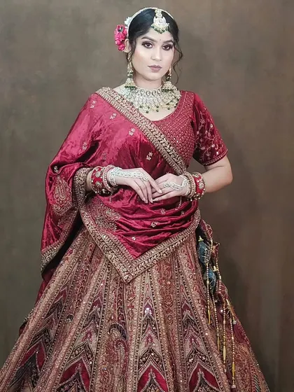 A full-length shot of a bride in a multi-colored lehenga with a velvet blouse. The dark green dupatta adds a rich contrast.