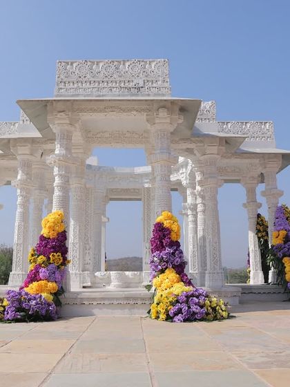 A wider shot of the Haldi mandap, showing how the floral installations were designed to complement and enhance the existing white marble structure.