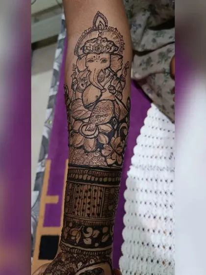 A detailed portrait of Lord Ganesha on the forearm, sitting atop a lotus. This is a great option for festivals or any auspicious event.