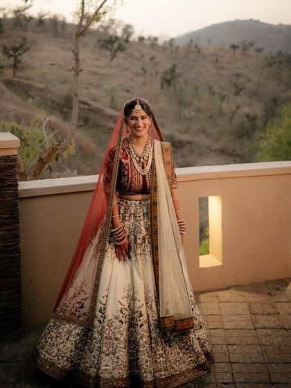A full-length shot of Sneha's unique JJ Valaya lehenga against a natural backdrop. The outfit's silhouette and colors are perfectly suited for a day wedding.
