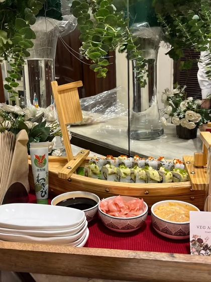 A beautifully arranged platter of Veg Assorted Sushi served on a wooden tray. The setup includes small bowls for soy sauce and pickled ginger, ready for guests to enjoy.