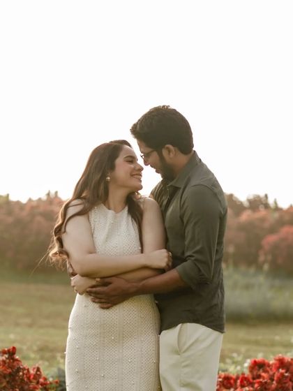 A warm, sun-kissed portrait of a couple embracing in a field. The golden light and their loving gaze make this a classic and timeless romantic pre-wedding photo.