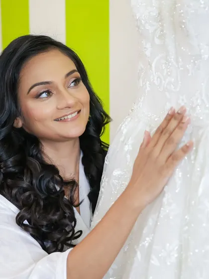 A quiet moment of anticipation before she puts on her gown. The bride's makeup is soft and romantic, with gentle curls framing her face, ready for the big day.