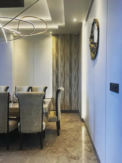 A side profile of the dining area, emphasizing the layered design. You can see the contrast between the textured wallpaper, the smooth wall panels, and the metallic wall art, all working together to create a visually rich environment.