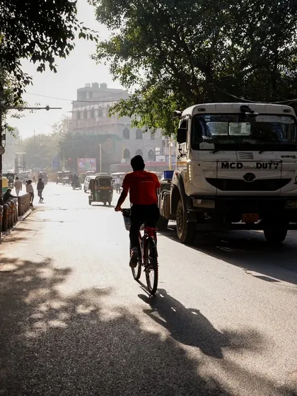 A cyclist shares the road with a truck in the early morning. Our tours are designed to experience the city's rhythm, from its quiet moments to its bustling peak.