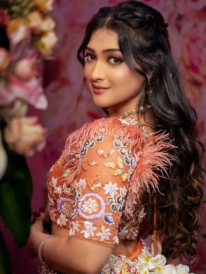 A lovely bridal portrait with a floral background. Her glance over the shoulder is both elegant and engaging, showcasing the detailed work on her blouse.