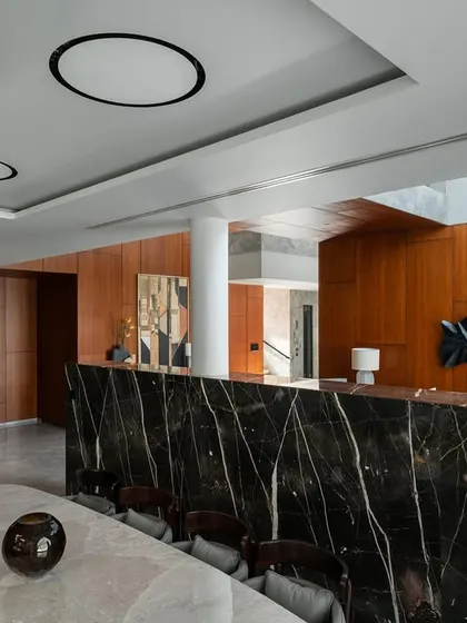 A bold, black marble partition with dramatic white veining separates the dining area while maintaining a visual connection to the rest of the open-plan space.