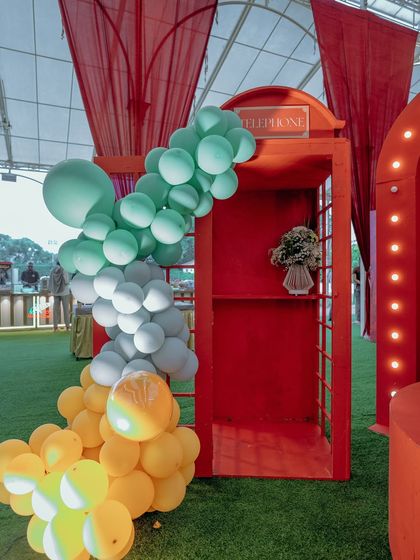 Even classic props get a whimsical twist. A traditional red telephone booth is transformed with a cascade of colorful balloons, serving as a unique photo spot within the vibrant carnival theme.