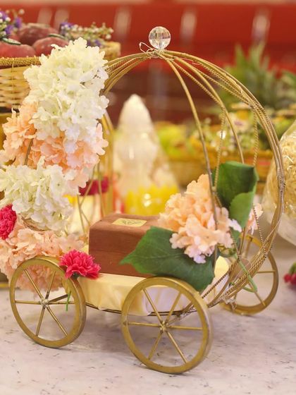 A unique and elegant prop for an engagement or wedding. This golden carriage, decorated with pastel flowers, can be used to hold rings or other small, significant items.