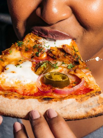 A slice loaded with toppings, including chicken, onions, and jalapeños, about to be enjoyed. This shows the heartiness of our pizzas.