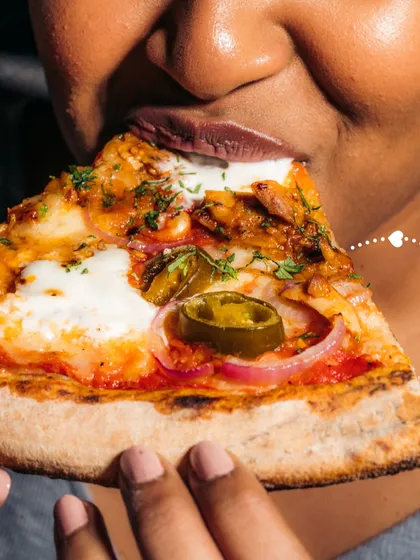 A slice loaded with toppings, including chicken, onions, and jalapeños, about to be enjoyed. This shows the heartiness of our pizzas.