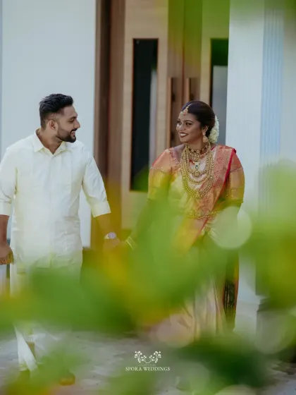 The couple walking together, seen through the leaves, creating an intimate and natural portrait of their bond.