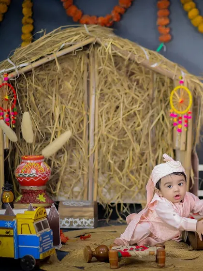 A baby crawling in our Lohri setup, surrounded by props like a miniature charpai (cot) and a colorful toy truck.