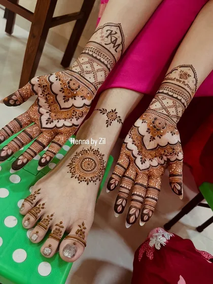 A complete set of personalized bridal henna, with the couple's initials 'KM' on the arms and a matching minimalist design on the feet.