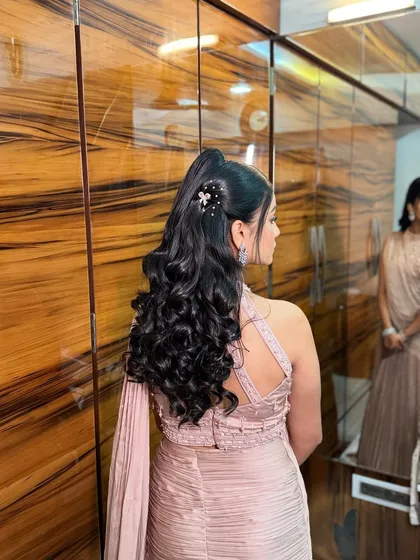A sleek and glamorous high ponytail with bouncy curls, perfect for a sangeet or reception look.